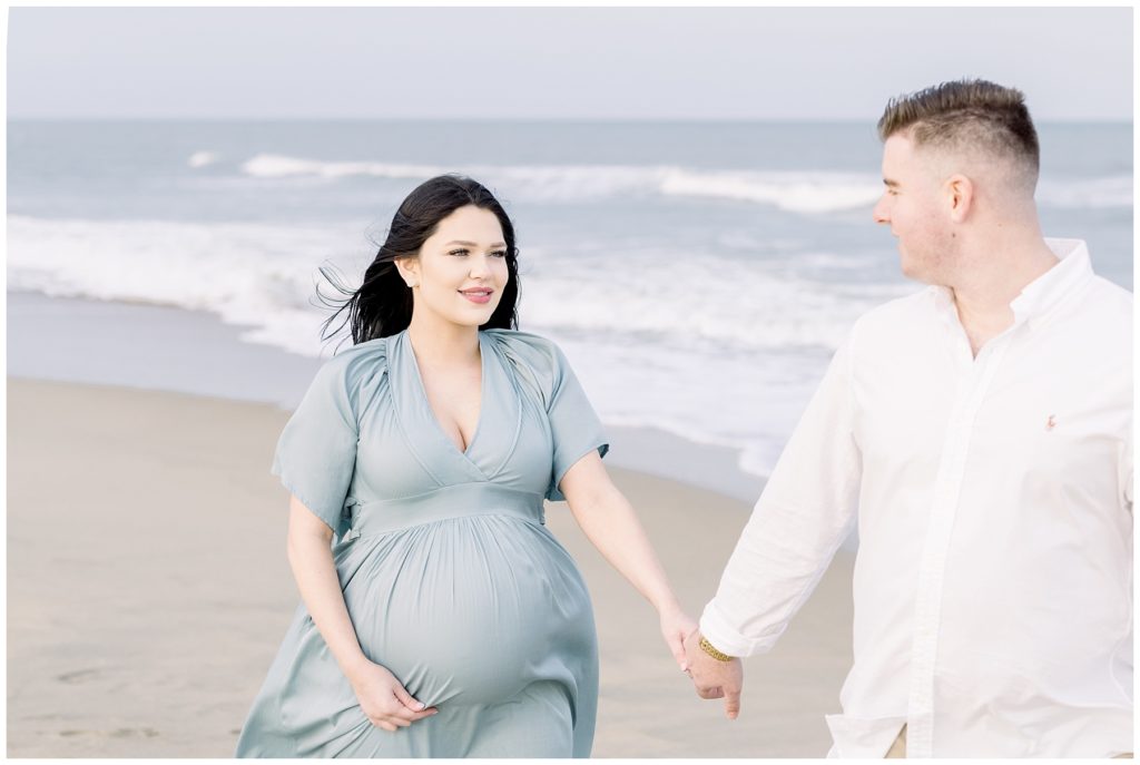 pregnant mother looking at her husband on the beach


