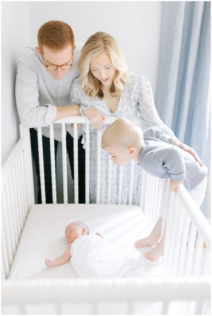 family looking at newborn in his crib
