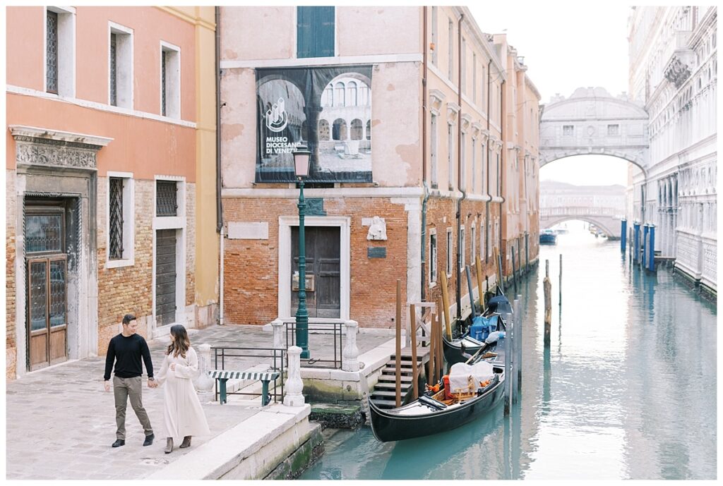 couple walking along the canal during their venetian babymoon
